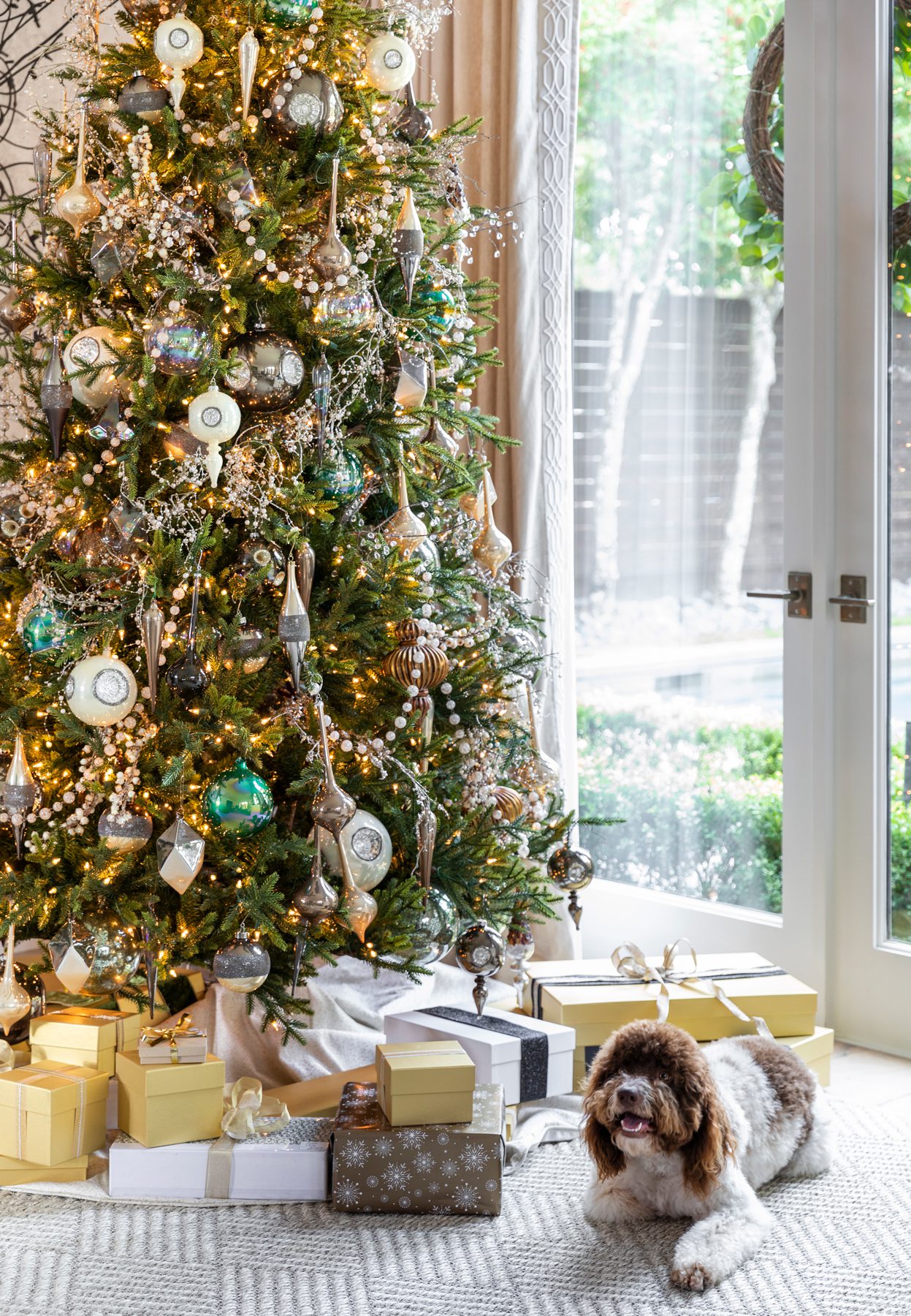 Professionally decorated Christmas tree in a residential home with a dog laying underneath.