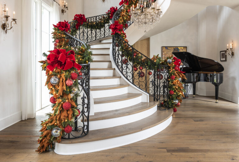 Professionally decorated residence for the holidays featuring garland on the staircase.