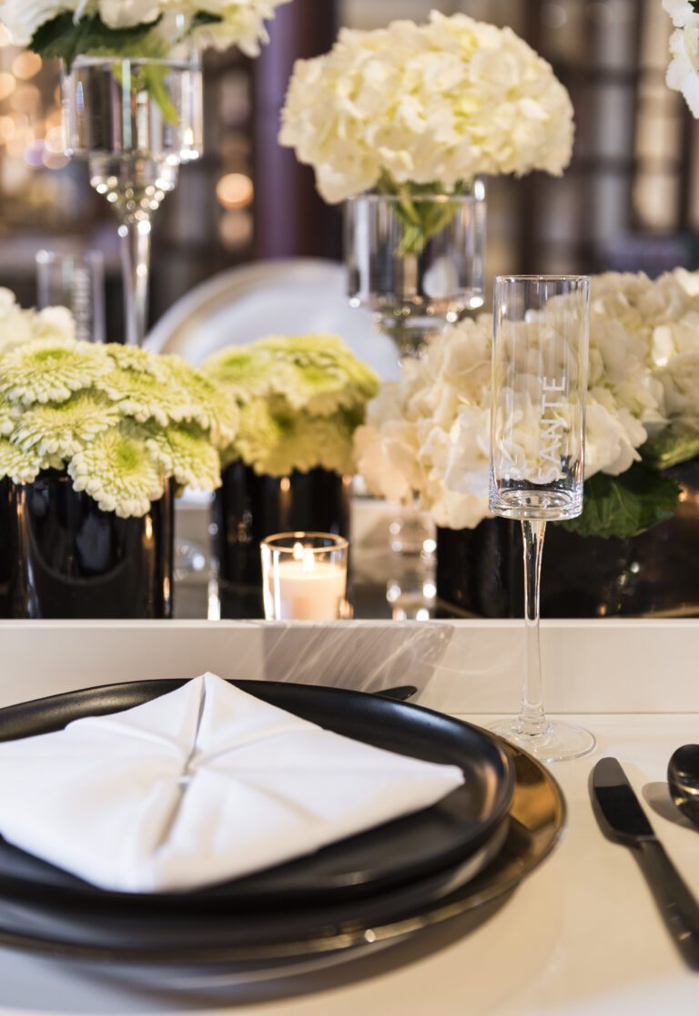 Place Setting at Wedding featuring white floral arrangement and candles.